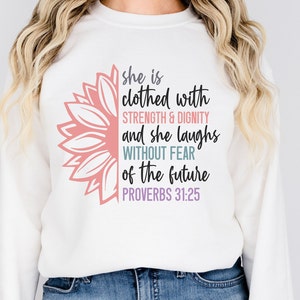 May include: White sweatshirt with a pink and white sunflower graphic and the text "she is clothed with STRENGTH & DIGNITY and she laughs WITHOUT FEAR of the future PROVERBS 31:25"