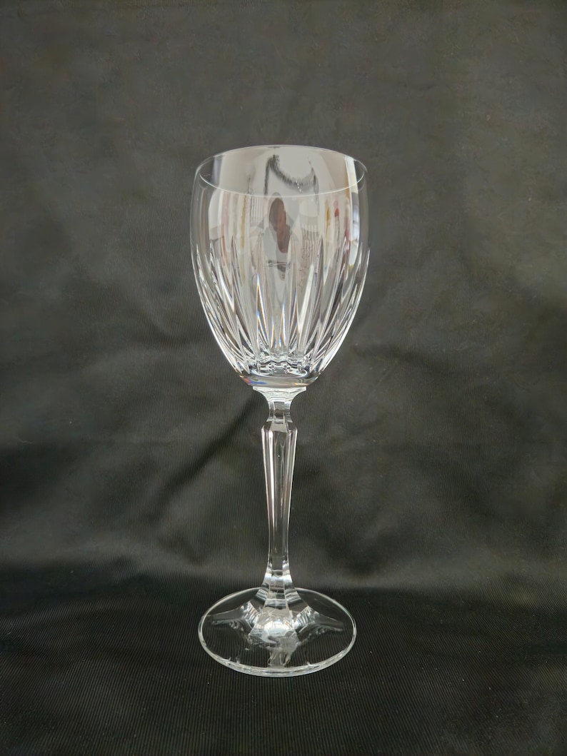 以下が含まれることがあります： 高い茎と広いボウルを持つ透明なガラス製のワイングラス。ボウルは、垂直な線でカットされたガラスのデザインが施されています。