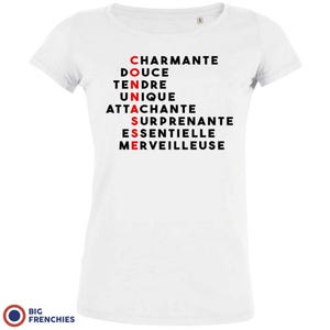 May include: White t-shirt with black text that reads "CHARMANTE, DOUCE, TENDRE, UNIQUE, ATTACHANTE, SURPRENANTE, ESSENTIELLE, MERVEILLEUSE" with the letters "CONNASSE" highlighted in red.