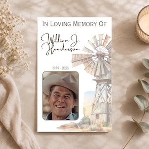 May include: A rectangular memorial card featuring the text IN LOVING MEMORY OF, the name William J. Henderson, and the years 1944-2023. The card displays a photograph of a smiling person wearing a cowboy hat, alongside a watercolour illustration of a windmill.