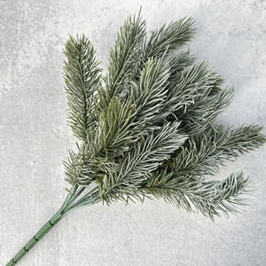 May include: A bunch of artificial frosted pine sprigs with green needles and a wire stem.