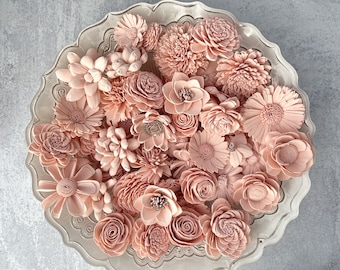 May include: A collection of blush pink sola wood flowers in a white decorative bowl. The flowers are arranged in a variety of shapes and sizes, creating a beautiful and delicate display.