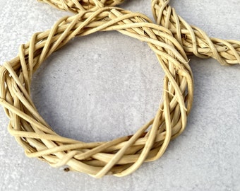 May include: A woven wreath made of natural, light brown twigs. The wreath is circular and has a simple, rustic design.