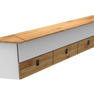 May include: A white cabinet with three wooden drawers and a wooden countertop. The cabinet has a slanted top and black drawer pulls.
