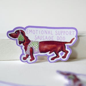 Sticker „Emotional Support Sausage Dog“ – Handgemalter Dackel im Pullunder, Süßer Hunde-Sticker auf lila Hintergrund, Dachshund Vinyl