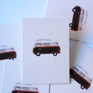 May include: A set of rectangular off-white cards, each featuring a watercolour illustration of a brown and white camper van with a surfboard on the roof. The van has a red stripe along the side, black wheels, and a yellow headlight detail.