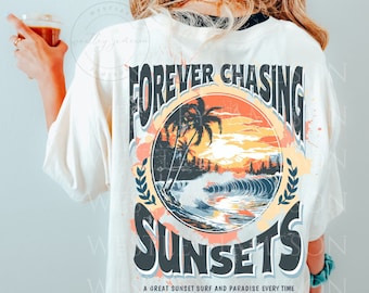 May include: A white t-shirt with a graphic print of a sunset scene with palm trees and waves. The text "FOREVER CHASING SUNSETS" is printed in a vintage style font. The text "A GREAT SUNSET SURF AND PARADISE EVERY TIME LET'S GO TO THE BEACH" is printed below the graphic.