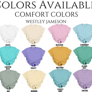 K&ouml;nnte beinhalten: Eine Tabelle mit 12 verschiedenen Farben von T-Shirts, die zum Kauf angeboten werden. Die Farben sind: Wei&szlig;, Elfenbein, Bl&uuml;te, Chambray, Lagunenblau, Violett, Senf, Inselriff, Bucht, Banane, Kreideminze und Orchidee.