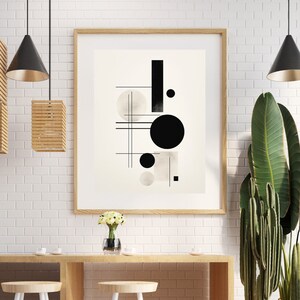 May include: A black and white abstract geometric print in a wooden frame hanging on a white brick wall above a wooden table with two white stools. A potted plant with green leaves is on the right side of the image.
