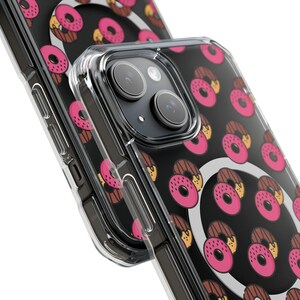 May include: A clear phone case with a black background and a repeating pattern of pink and brown donuts. The case has a raised camera bump.