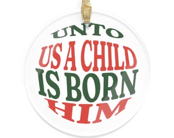 Puede incluir: Adorno navideño redondo y transparente con la frase "UNTO US A CHILD IS BORN HIM" en letras rojas y verdes. Incluye una cinta dorada para colgar.
