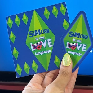 May include: Three stickers with a green diamond shape and the text "Simlish is my Love Language" in blue and white text. The stickers feature a cartoon character with a green eye and a pink heart.