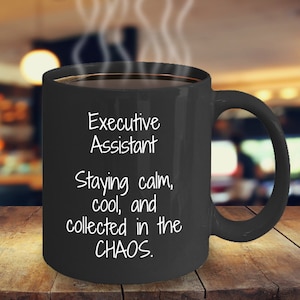 May include: Black coffee mug with white text that reads "Executive Assistant Staying calm, cool, and collected in the CHAOS."