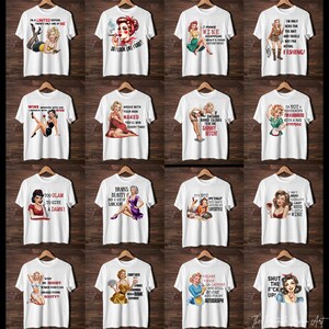 May include: A set of 16 white t-shirts with various humorous and sassy sayings printed on them. The sayings are in a vintage style font and feature pin-up style illustrations of women.