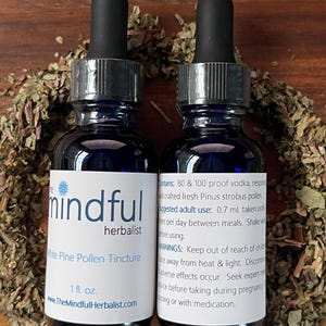 May include: Two blue glass bottles of White Pine Pollen Tincture with black droppers, labeled "mindful herbalist." Each bottle contains 1 fl. oz. and is surrounded by dried herbs. The label includes usage instructions and warnings.
