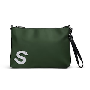 May include: A dark green clutch bag with a white snake-shaped "S" logo. The bag has a black zipper and a black wrist strap. The bag is rectangular and appears to be made of a smooth, synthetic material.