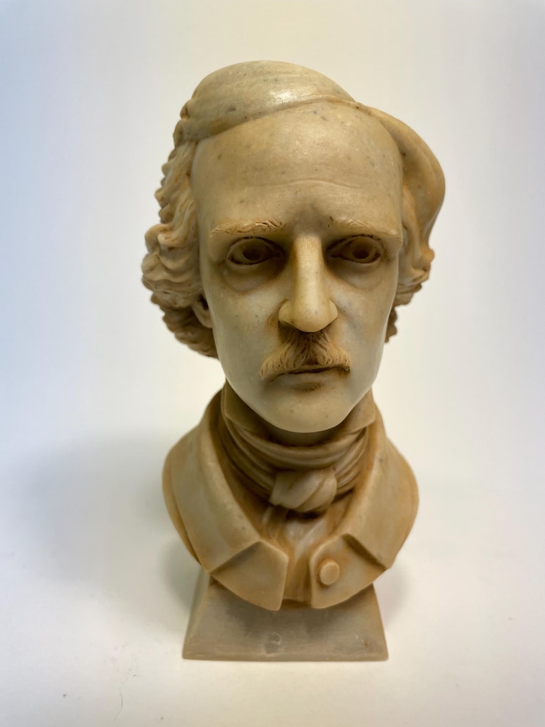 May include: A white ceramic bust of a man with a mustache and a cap. The bust is on a white base.