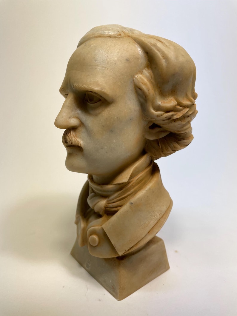 May include: A beige marble bust sculpture of a man with short, wavy hair. The bust is on a square base.
