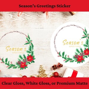 Könnte beinhalten: Runder Aufkleber mit dem goldenen Schriftzug "Season's Greetings", umgeben von einem Kranz aus grünen Tannenzweigen, roten Weihnachtssternen und Tannenzapfen. Erhältlich in glänzend klar, glänzend weiß oder Premium-Matt.
