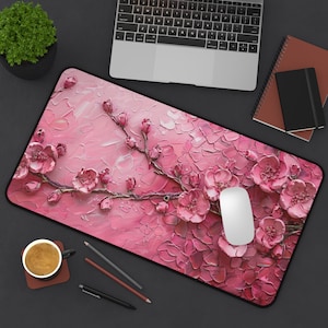 May include: Pink floral mouse pad with a white mouse on top. The mouse pad features a painterly design of pink flowers and leaves.