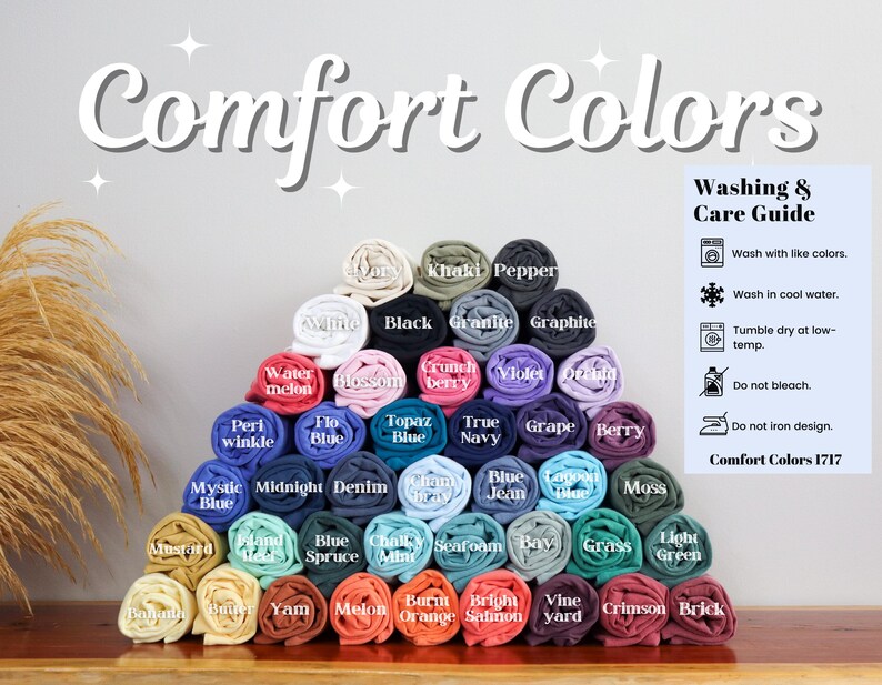 Pode incluir: Uma exibi&ccedil;&atilde;o de camisetas enroladas em v&aacute;rias cores, incluindo preto, branco, azul, verde, vermelho e amarelo. As camisetas est&atilde;o dispostas em forma de pir&acirc;mide e etiquetadas com seus nomes de cores. O texto "Comfort Colors 1717" &eacute; vis&iacute;vel na parte inferior da imagem.