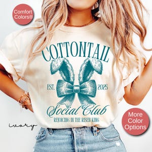 May include: A white t-shirt with a teal graphic of a bunny tail bow with the text "COTTONTAIL EST. 2025 Social Club REJOICING IN THE RISEN KING"