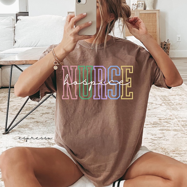 May include: A brown t-shirt with the text "NURSE hospice" in colourful letters. The text is outlined in white.