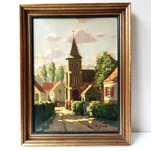 Può includere: Dipinto a olio di una scena di villaggio europeo in una cornice dorata. L'opera raffigura una chiesa con un alto campanile, circondata da case e alberi. Il dipinto è firmato "Ph. Jacoby."