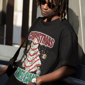 May include: A black t-shirt with a Christmas tree cake design. The text "Christmas Tree Cake" is printed on the shirt in green and white.