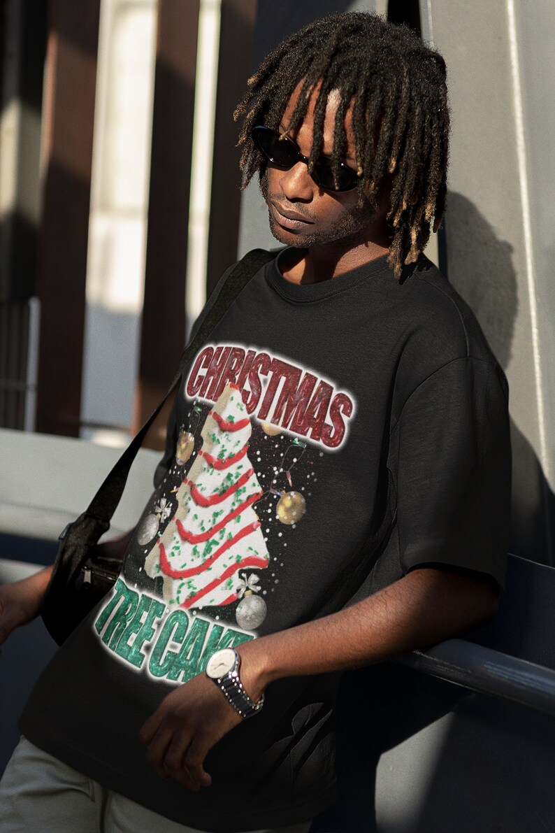 May include: A black t-shirt with a Christmas tree cake design. The text "Christmas Tree Cake" is printed on the shirt in green and white.