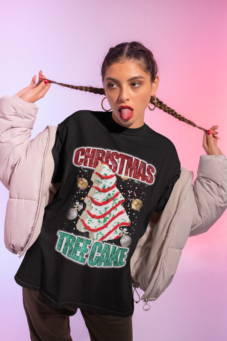 May include: A black t-shirt with a white Christmas tree cake design. The text "Christmas Tree Cake" is written in green and red letters.