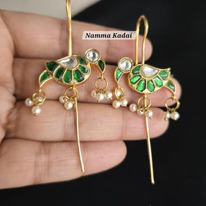May include: Gold-toned earrings with a bird design. The earrings feature green enamel detailing, clear stone accents, and small pearl drops. The text "Namma Kadai" is visible in the image.