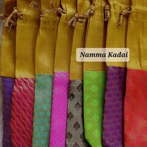 May include: A set of nine gold drawstring pouches with colorful patterned fabric bottoms. The pouches are arranged in a row and have a label that reads "Namma Kadai".