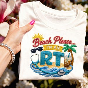 May include: White t-shirt with an embroidered design featuring the text "Beach Please... I'm an RT." The design includes a sun, sunglasses, a stethoscope, a palm tree, and a beverage. The shirt is a crew neck.