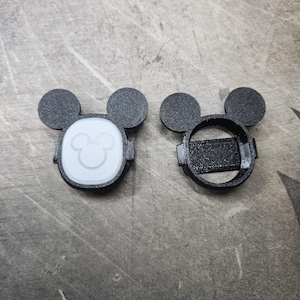 Puede incluir: Dos cubiertas de pl&aacute;stico negro en forma de Mickey Mouse para un reloj inteligente. Una cubierta tiene una cara de Mickey Mouse blanca con un contorno blanco. La otra cubierta es un marco hueco.