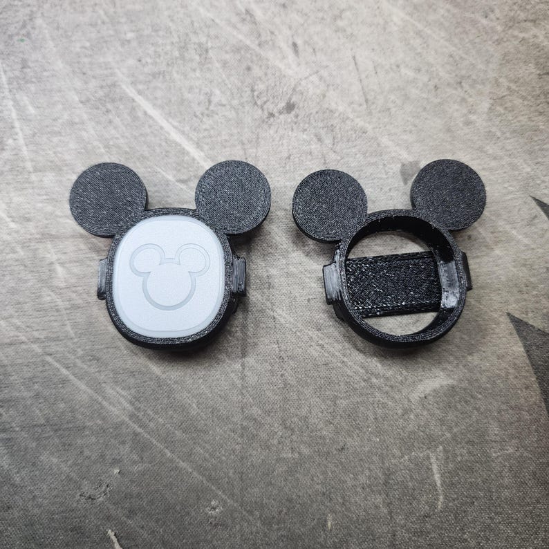 Puede incluir: Dos cubiertas de pl&aacute;stico negro en forma de Mickey Mouse para un reloj inteligente. Una cubierta tiene una cara de Mickey Mouse blanca con un contorno blanco. La otra cubierta es un marco hueco.