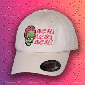 Può includere: Un cappello da baseball bianco con una testa di alieno verde e le parole "ACK! ACK! ACK!" ricamate in rosa. Il cappello ha un'etichetta Flexfit nera con le parole "The Original Flexfit L/XL It Fits Your Life."
