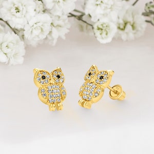 May include: A pair of gold owl stud earrings with clear and black cubic zirconia stones.