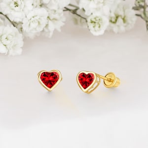 May include: A pair of gold heart-shaped earrings with red gemstone accents.