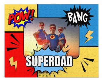 Może przedstawiać: Kolorowa układanka przedstawiająca rodzinę przebraną za superbohaterów. Puzzle mają motyw komiksowy ze słowami "POW!", "BANG" i "SUPERDAD" w dymkach. Rodzina ma na sobie czerwone peleryny i maski.