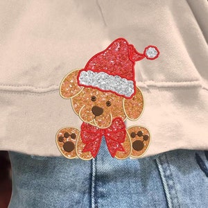 May include: A beige sweatshirt with a sparkly red and white Christmas puppy applique. The puppy is wearing a Santa hat and has a red bow.