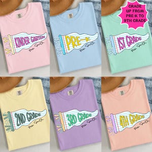 May include: A collection of six short-sleeved crew neck t-shirts in pastel pink, light blue, mint green, pale yellow, lavender, and peach. Each shirt features a graphic of a pennant flag with lined paper texture and the text Mrs. Smith.