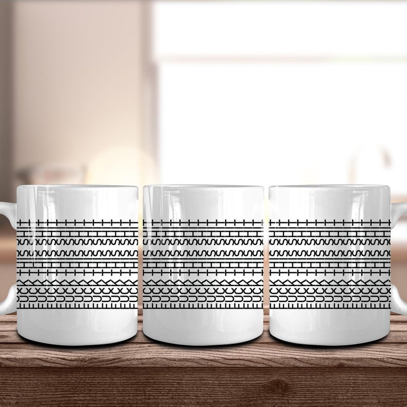 May include: Three white ceramic mugs with a black geometric pattern. The pattern consists of horizontal lines, zigzags, and other shapes. The mugs are sitting on a wooden surface.