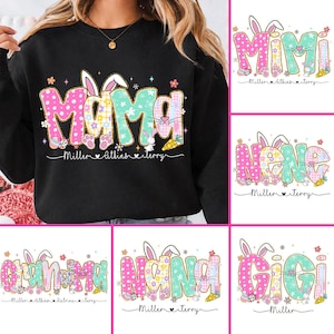 May include: Black sweatshirt with the word "Mama" in pink and teal letters, decorated with bunny ears, flowers, and a carrot. The design includes the text "Miller, Atkins, terry". Additional designs include "Mimi", "Nana", "Grammy", and "Gigi".