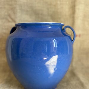 May include: A blue ceramic vase with two handles. The vase has a white rim and a glossy finish.
