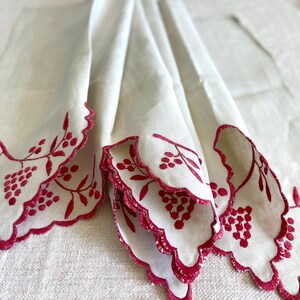 May include: White handkerchiefs with scalloped edges and embroidered red berry and leaf designs. The handkerchiefs are folded, showcasing the intricate details of the embroidery and the delicate fabric.