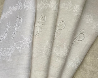 May include: Set of four white linen napkins with embroidered floral borders and a single letter 'P' in the center of each napkin.