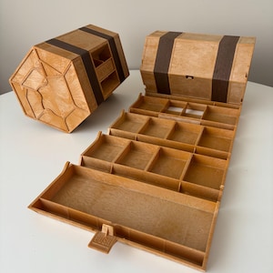 Op de afbeelding: Een vintage houten opbergdoos, open en gesloten, met meerdere compartimenten. De doos is lichtbruin met donkerbruine accenten en een drukknopsluiting. De open doos onthult verschillende kleine opbergruimtes.