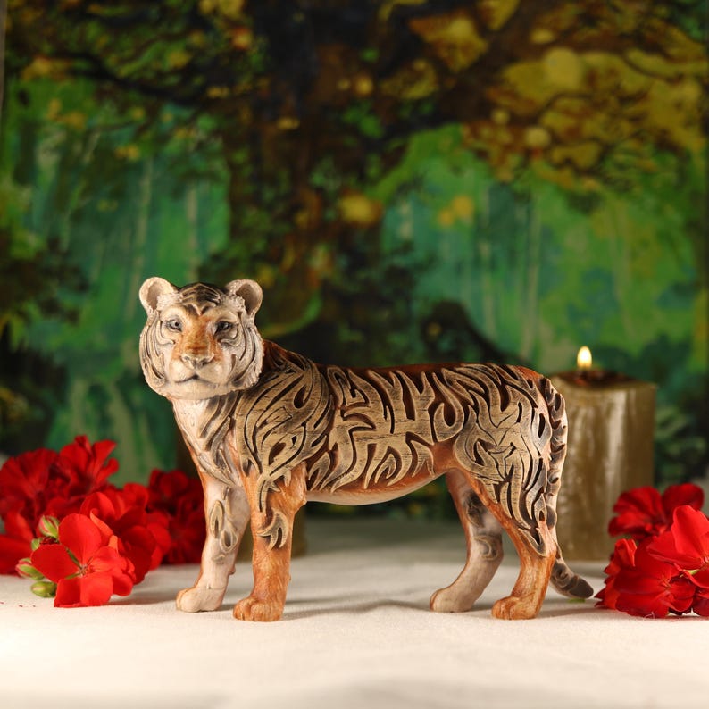 May include: A detailed ceramic tiger figurine with intricate brown and black markings. The tiger is standing on a white surface with red flowers in the background.