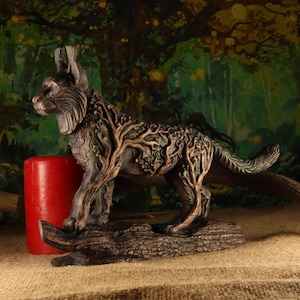 Op de afbeelding: Een gedetailleerde sculptuur van een lynx, met boomachtige patronen die zijn lichaam bedekken. De lynx staat op een boomstam, met een rode kaars aan zijn zijde. Het kleurenpalet omvat tinten bruin, groen en rood, wat een naturalistische esthetiek creëert.